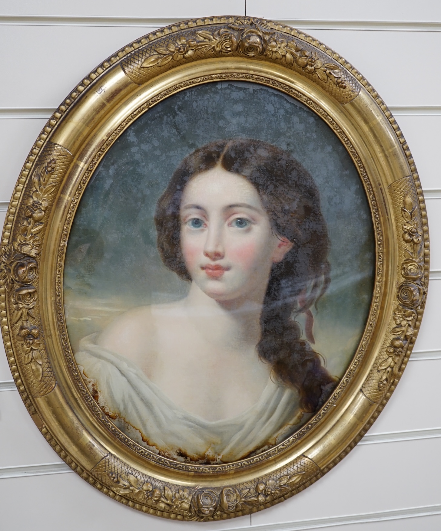 19th century School, reverse glass painted oval panel, Study of a young beauty, 44 x 36cm, housed in a gilt frame. Condition - poor to fair